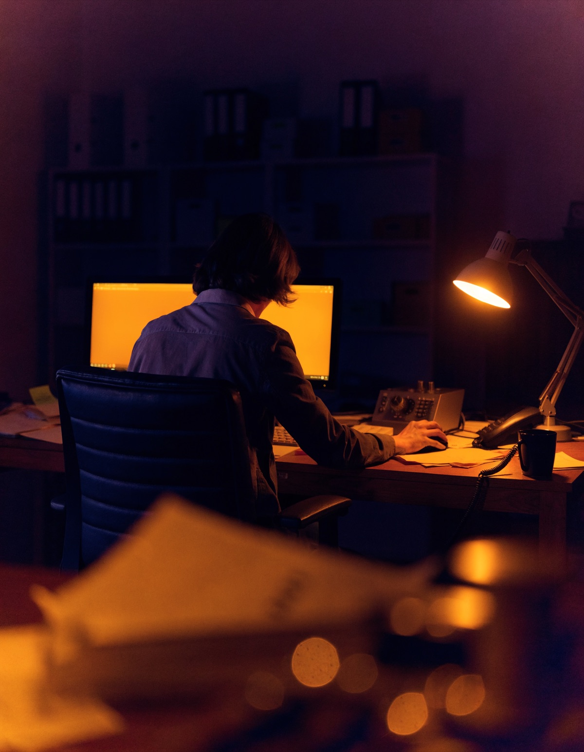 An operator working alone at a desk late at night, the weight of the whole operation on them